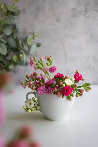 Белая чашка с весенними цветами вместо кофе на столе крупным планом. Высокое качество фото - Фото, изображение