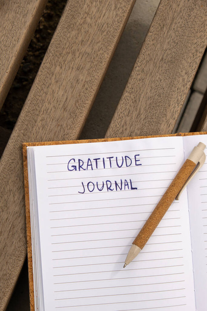 Kirjoittaminen Kiitollisuus Journal puinen penkki. Tänään olen kiitollinen. Itse löytö päiväkirja, itsetutkiskelua luova kirjoittaminen, itse kasvu henkilökohtainen kehitys käsite. Omahoito hyvinvointi hengellinen - Valokuva, kuva