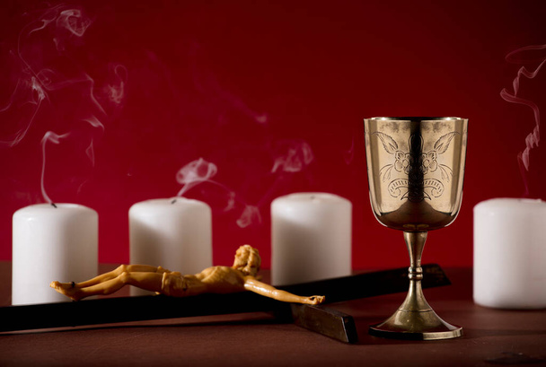 cálice dourado com crucifixo e velas extintas com fundo vermelho fumaça - Foto, Imagem