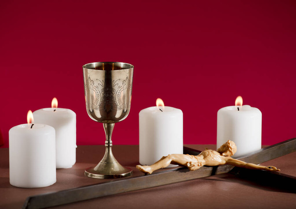cálice dourado com crucifixo e queimando velas fundo vermelho - Foto, Imagem
