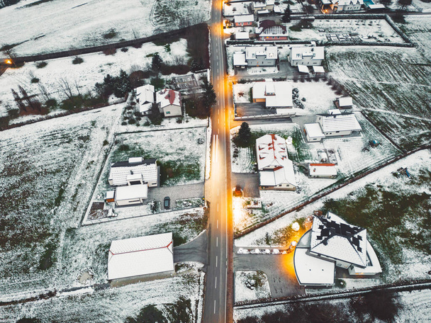 Aerial view of suburban community in winter time in the evening. Snow on the grounds, dark, street lights shining.  - Φωτογραφία, εικόνα