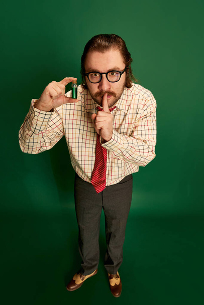 Chemist. Portrait of retro mature man with moustache and beard in eyeglasses posing in vintage fashion clothes over dark green background. Concept of retro style, emotions, business, work - Photo, Image