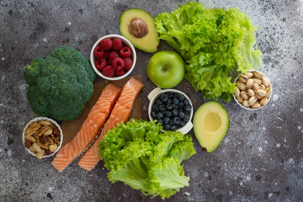 Gezond voedsel schoon voedsel selectie: fruit, groenten, superfoods, zalm vis, bladgroenten op grijze beton achtergrond - Foto, afbeelding