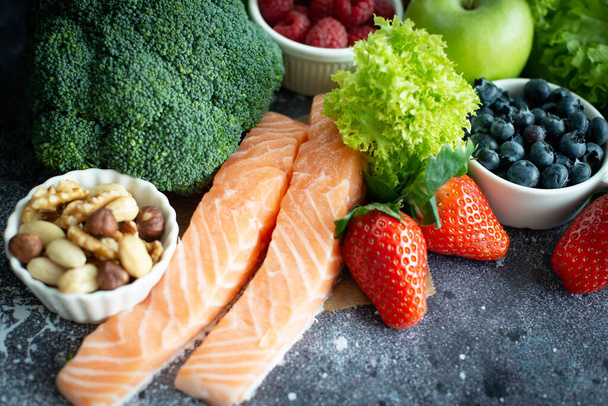 Gezond voedsel selectie: fruit, groenten, noten, superfoods, bessen, bladgroenten op een grijze betonnen achtergrond - Foto, afbeelding