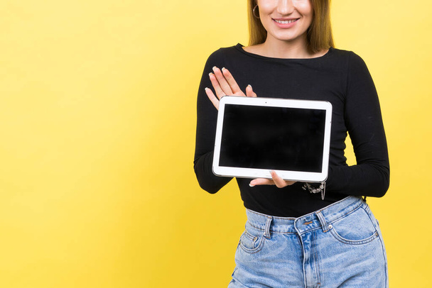 Smart intelligent caucasian young woman student using digital tablet isolated on yellow background - Foto, Imagen
