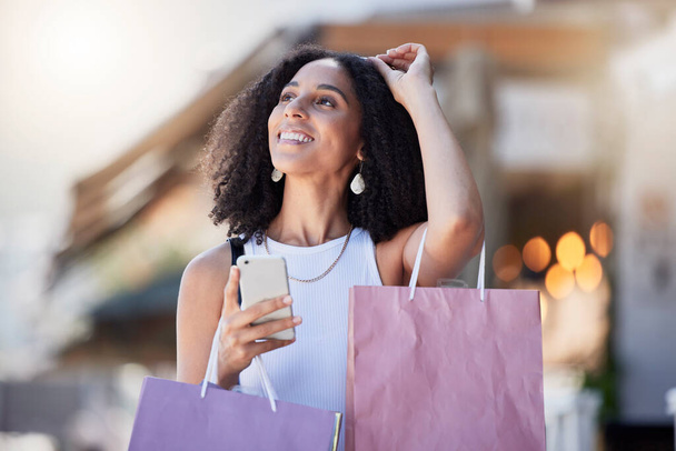 割引のためのオンラインショップアプリ上の顧客の黒人女性、電話や小売ショッピングバッグ。背景がぼやけている街の通りに女性の店舗プロモーション、都市や商業モバイルネットワーク. - 写真・画像