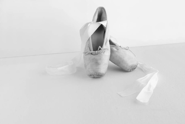 Vieille paire de chaussures de ballet soigneusement disposées sur un fond sombre avec copyspace et vieilles chaussures pointes. image en noir et blanc - Photo, image