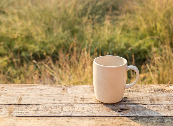 weiße Kaffeetasse auf Holztisch in der Morgensonne - Foto, Bild