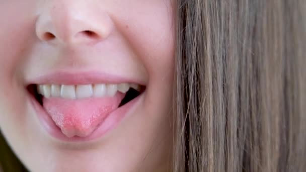 spielerisches Videomädchen schöner Mund zeigt kleine Zunge spöttisch scherzhaft flirten nicht einverstanden Nahaufnahme Mund und Zunge reinigen sogar weiße Zähne lecken Zähne lecken Lippen haben Spaß strecken Ihre Zunge - Filmmaterial, Video