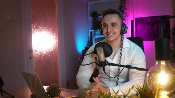 One man caucasian male blogger or vlogger gesticulating while streaming video podcast in broadcasting studio use microphone and headphones famous influencer shooting video for channel podcast - Кадры, видео