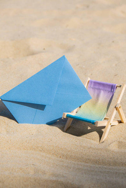 Sunny holidays on the beach sand beach accessories. Sun lounger stand sea with blue empty envelope Copy space for your text. Wooden beach chairs. Summer holiday vacation concept - 写真・画像