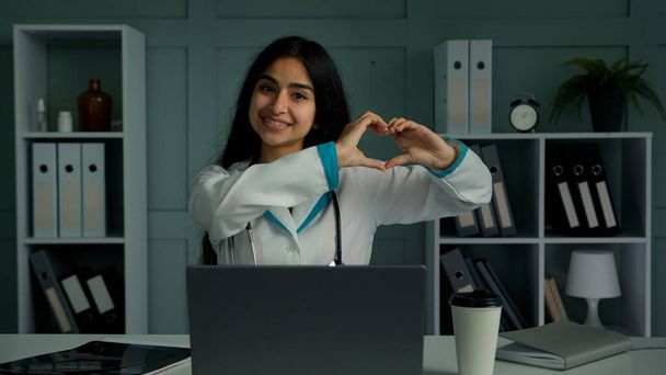 Fürsorgliche aufrichtige junge Frau arabisch latina Kardiologe Medizinstudent Kardiologie Medizin Arzt machen Liebe Symbol Herz Organform zeigen menschliche Großzügigkeit Pflege Unterstützung Wohltätigkeit Spendenkonzept - Foto, Bild