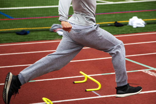 High school track runner running over yellow mini hurdles during track practice. - Foto, afbeelding
