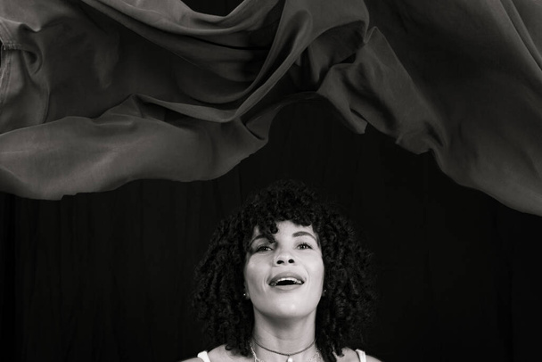 Чорно-білий портрет жінки кидає тканину в повітря. Ізольовані на чорному тлі
. - Фото, зображення