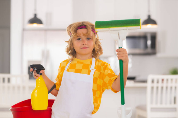 Kind gebruik stofdoek en handschoenen voor het reinigen. Grappig kind dweilen huis. Schoonmaakaccessoire, schoonmaakmiddelen. Huishouden en schoonmaken - Foto, afbeelding