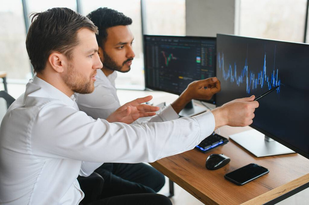 Two successful trader in formalwear pointing at display, analyzing stat and dynamic on forex charts, working in office together. - Foto, imagen