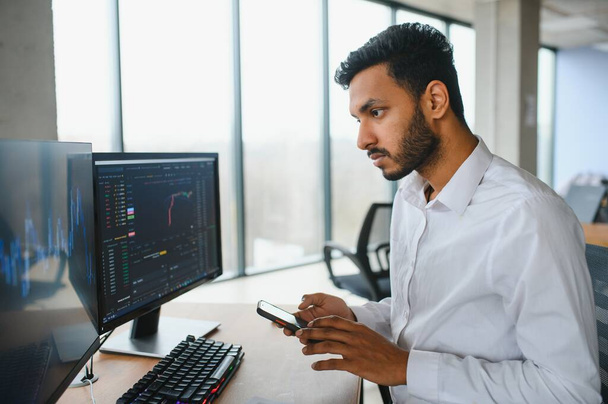 Portrait of a positive successful Indian or Arabian trader, stock market broker, Crypto charts on laptop screen. - Fotografie, Obrázek