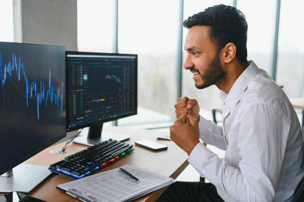 Young indian business man trader looking at computer screen with trading charts reflecting in eyeglasses watching stock trading market financial data growth concept, close up - Foto, Bild