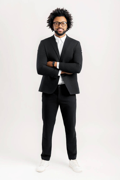 Orgoglioso uomo d'affari afro-americano in abito nero in piedi con le braccia incrociate isolato su bianco, foto a figura intera di imprenditore maschio di successo in posa sicura, spazio copia, pubblicità - Foto, immagini