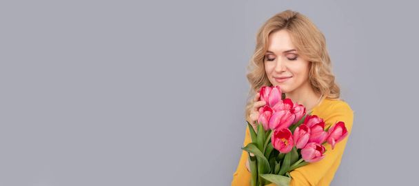smiling woman smell tulips. lady hold flowers for spring holiday. girl with bouquet. Woman isolated face portrait, banner with mock up copy space - Foto, Bild