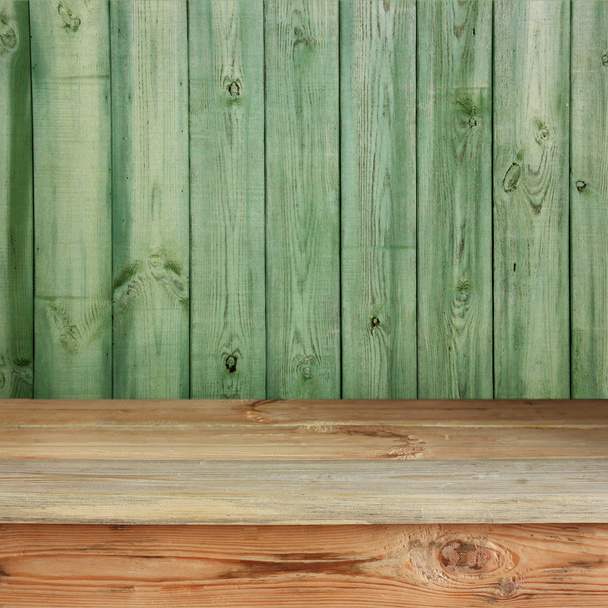 Wooden table against a green wall from boards. - Fotografie, Obrázek