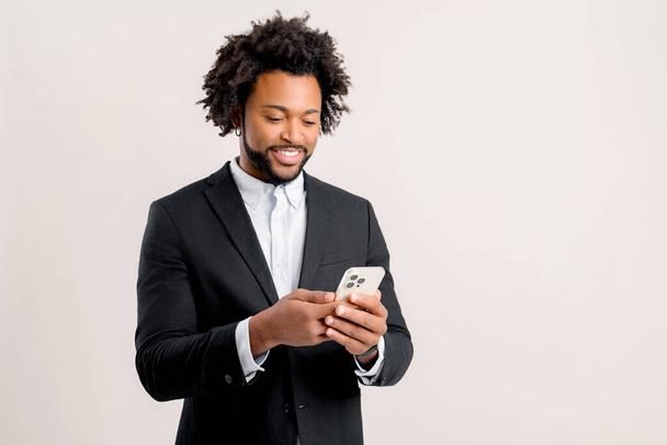Happy businessman in formal office wear using smartphone isolated on white, african-american guy chatting online, using new mobile app, testing, web surfing - Fotografie, Obrázek