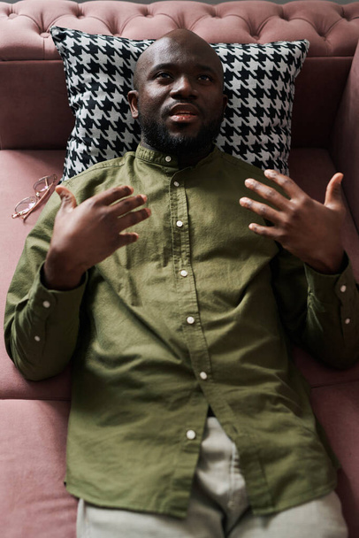Yllä kuva nuori musta mies casualwear selittää hänen ongelmia psykoanalyytikko tai ohjaaja kun makaa sohvalla istunnon aikana - Valokuva, kuva