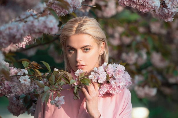 Girl in in blossoms cherry sakura. Outdoor portrait of beautiful sensual fashion girls posing near blooming tree with pink flowers - Foto, Bild
