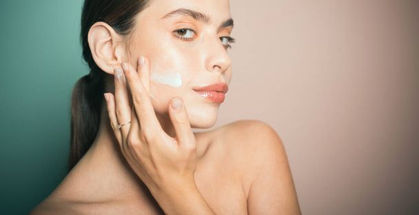 Sexy healthy woman applying cream or lotion with moisturizer to skin face. Perfect pure skin. Healthy and wellness concept. Natural beauty and no make up concept - Photo, Image