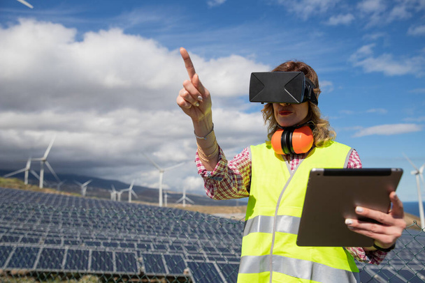 Güneş çiftliğindeki kadın bir mühendis sanal gerçeklik kulaklıkları ve tablet kullanarak çalışıyor.. - Fotoğraf, Görsel