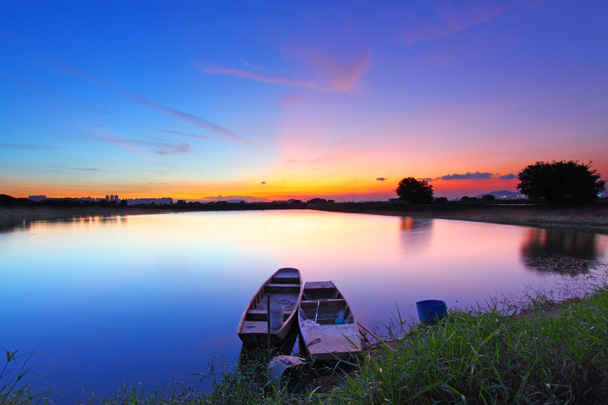 Sunset along the pond with two boats and two magical color on sk - Photo, Image
