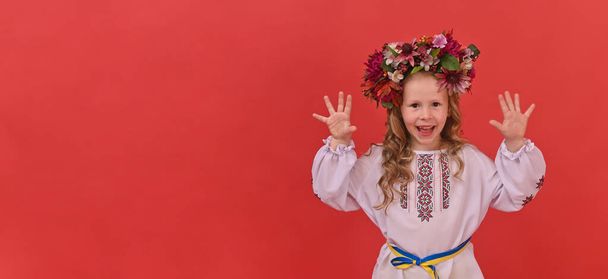 banner girl in Ukrainian embroidery with a wreath on a red background. copy space - Foto, immagini