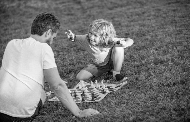 happy family of father and son boy playing chess on green grass in park outdoor, chess game. - Fotografie, Obrázek
