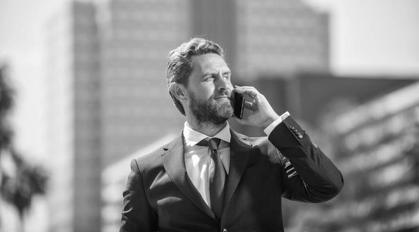 successful businessman in suit speaking on phone standing outdoor, communication. - Zdjęcie, obraz