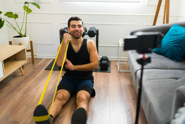 Attractive happy man filming a home workout video for his social media blog about fitness lifestyle - Foto, Imagem