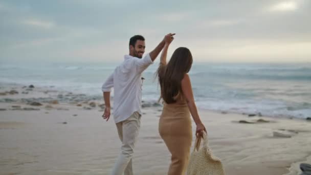 Egy szerelmespár, akik az óceán partján futnak. Két ember sétált kint a vízparton. Etnikai házastársak nevetnek a romantikus randin a szabadban. Mosolygó felnőttek mennek ki a tenger partján. A természet szabadidős koncepciója  - Felvétel, videó