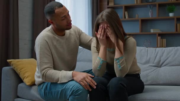 Guilty african american man apologizing to crying woman caring husband boyfriend calm sad stressed wife consoling girlfriend supporting saying sorry asking forgiveness after conflict family quarrel - Záběry, video