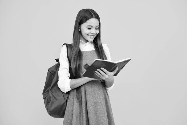 Schoolgirl, teenage student girl hold book on yellow isolated studio background. School and education concept. Back to school - Photo, Image