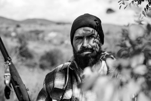 Poacher in the Forest. Hunter with shotgun gun on hunt. Bearded hunter man holding gun and walking in forest - Valokuva, kuva