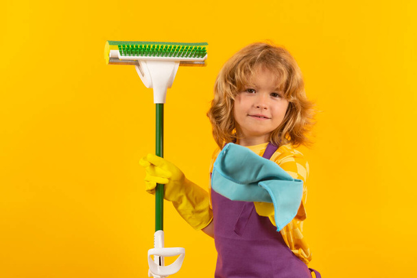 Dziecko robi prace domowe. Dzieci pomagające w sprzątaniu domu. Pokojówka w domu. słodkie dziecko chłopiec pomaga w sprzątaniu na żółty studio backdround - Zdjęcie, obraz