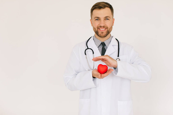 Счастливый врач-кардиолог держит сердце на белом фоне - Фото, изображение