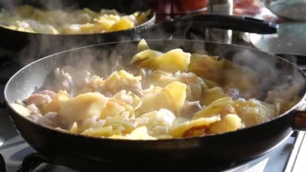 Smażone ziemniaki na patelni z przyprawami i kawałkami mięsa w domowej kuchni. Para nad gorącym jedzeniem. - Materiał filmowy, wideo