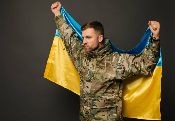 Portrait of a courageous Ukrainian military man holding the flag of Ukraine, freedom concept - Photo, Image