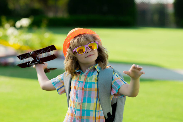 夏の野外でおもちゃの紙の翼で遊ぶ幸せな子供。旅行や子供の休暇のコンセプト。想像力と自由 - 写真・画像