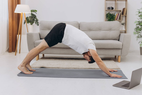 Handsome bearded man doing hamstring stretch exercise at home. - Foto, imagen