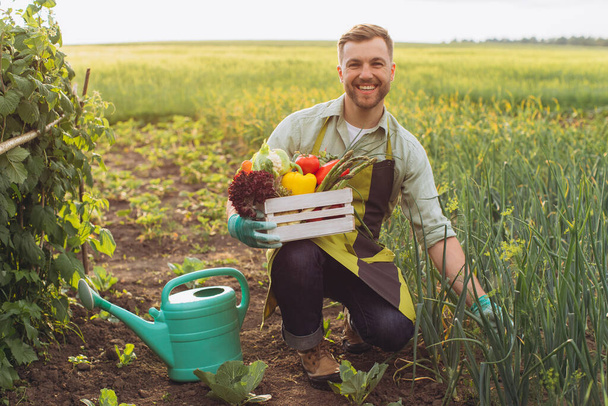 新鮮な野菜とバスケットを保持し、庭で働く幸せな農家の男、園芸の概念 - 写真・画像