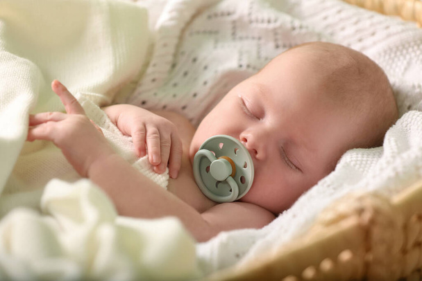 Cute newborn baby sleeping on white blanket in wicker crib, closeup - Φωτογραφία, εικόνα