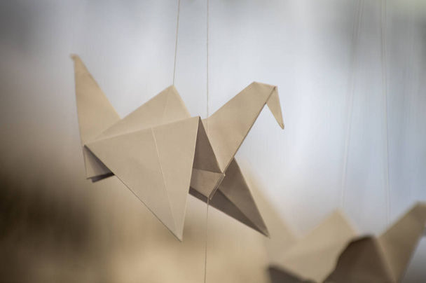 Японские сложенные журавли Оригами висят на струнах. Сотни бумажных птиц ручной работы, изолированных копировальным пространством. Тема 1000 тысяч крановых скульптур. Символ мира, веры, здоровья, желаний, надежды - Фото, изображение