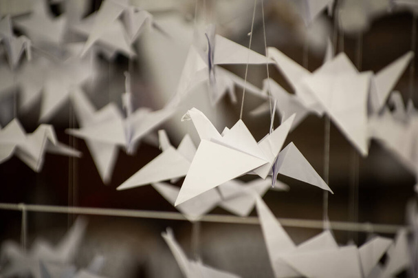 Japanese folded Origami cranes hanging on with strings. Hundreds handmade paper birds isolated with copy space. 1000 thousand crane tsuru sculpture topic. Symbol of peace, faith, health, wishes, hope - Fotografie, Obrázek