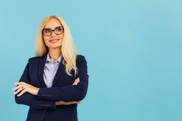 Portret van een aantrekkelijke zakenvrouw van middelbare leeftijd op een blauwe achtergrond - Foto, afbeelding